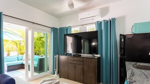 Een moderne woonkamer met een bank, een televisie, een kast en een schuifpui naar een balkon.