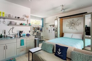 Quarto moderno com cama, mesa de cabeceira e um espaço de trabalho com cadeira.