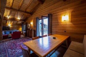 A wooden interior with a dining table, chairs, a sofa, and a patterned rug. - Chalet Paradis Blanc - 3 bedroom chalet near the golf course (Chamonix-Mont-Blanc)