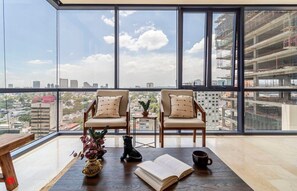 Ein geräumiger Balkon mit zwei Stühlen, einem kleinen Tisch und Blick auf die Stadtlandschaft.