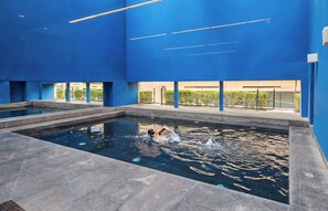 An indoor swimming pool with clear water, surrounded by blue walls and a tiled floor. - Miyana by Kukun | 3BR apartment (Ciudad de México)