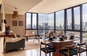 Ein modernes Wohnzimmer mit großen Fenstern, einem Essbereich und einem Sofa.