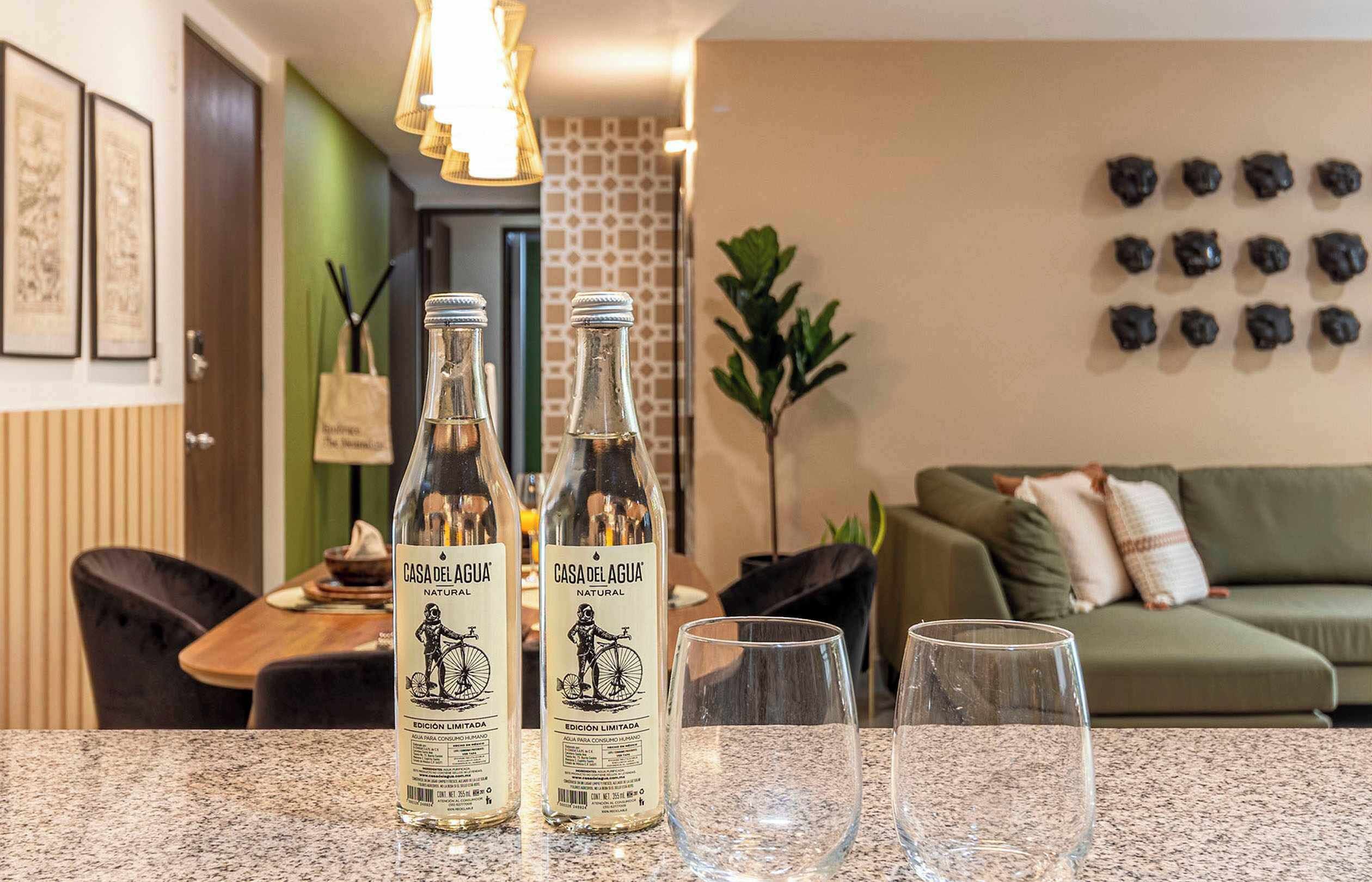 Two bottles of Casa del Agua natural wine on a counter with two glasses.