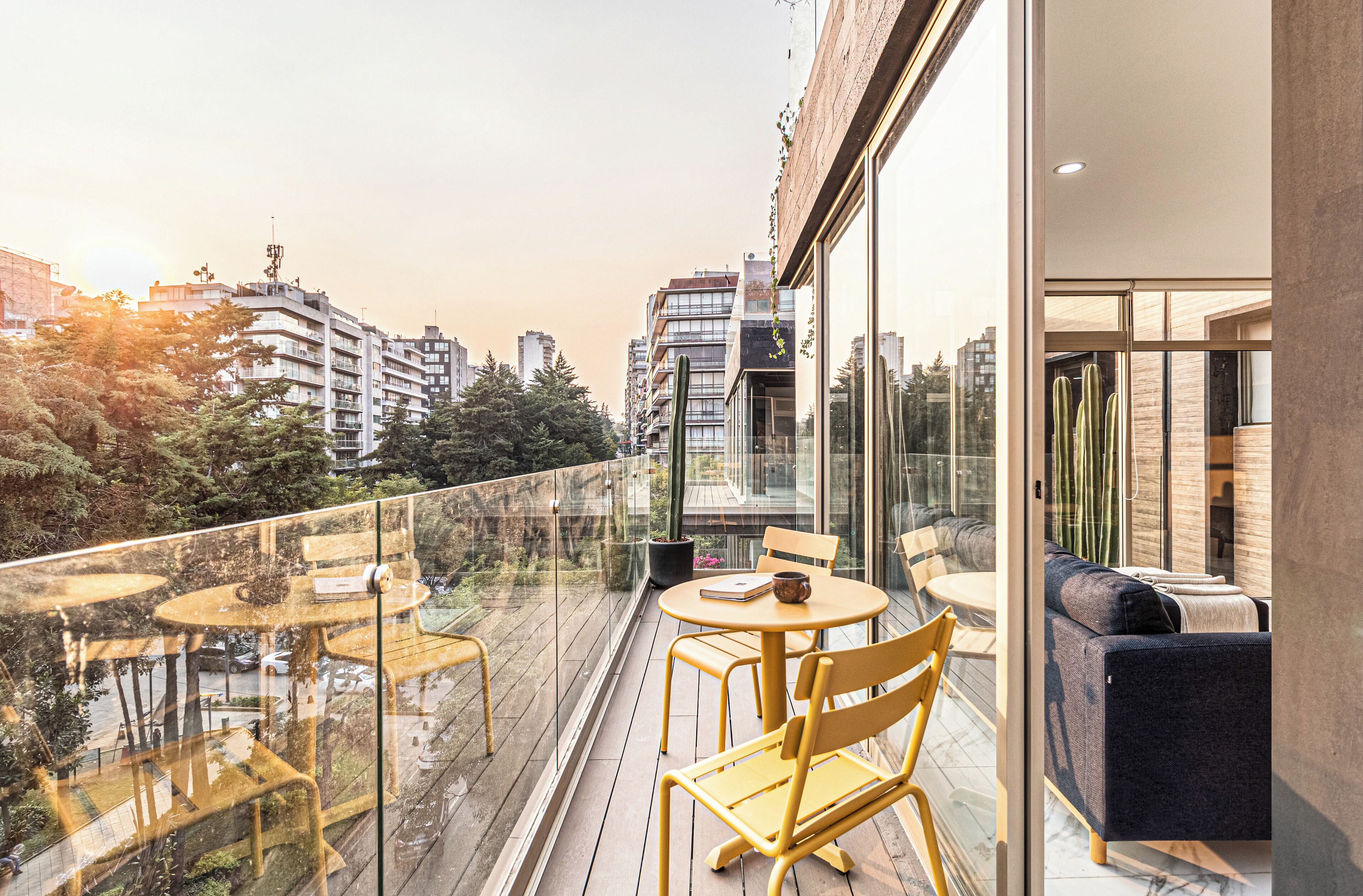 Un balcon moderne avec des garde-corps en verre, des meubles en bois et une vue sur le paysage urbain.