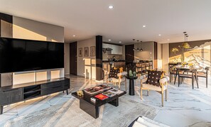 A modern living room with a large flat-screen TV, a coffee table with books, and a dining area with chairs and a table. - Casa Horacio by Kukun (Ciudad de México)