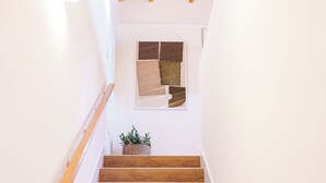 Una escalera de madera junto a una pared blanca y un ventanal con un diseño geométrico.