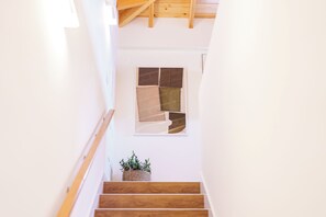 A wooden staircase with a white wall and a window with a geometric pattern. - Casa Amarela do Redondo - Seixal - Madeira Island (Seixal)
