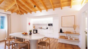 Una cocina moderna con armarios blancos, una mesa de comedor con sillas y un techo de madera.