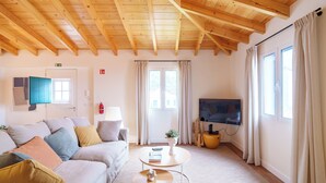 Una sala de estar con un sofá, una mesa de centro, un televisor y una ventana con cortinas.