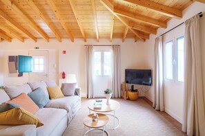A living room with a sofa, a coffee table, a TV, and a window with curtains. - Casa Amarela do Redondo - Seixal - Madeira Island (Seixal)