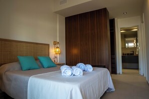 Een hotelkamer met een bed, een houten hoofdeinde, een wandlamp en uitzicht op de badkamer.