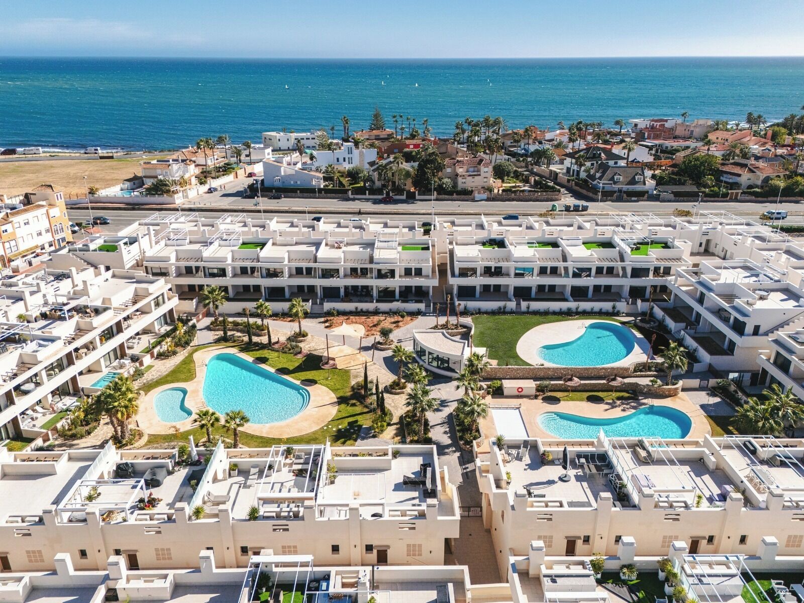 A resort with multiple swimming pools, a beach, and a view of the ocean.
