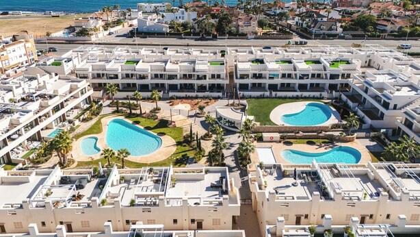 Ett semesterparadis med flera pooler, en strand och utsikt över havet.