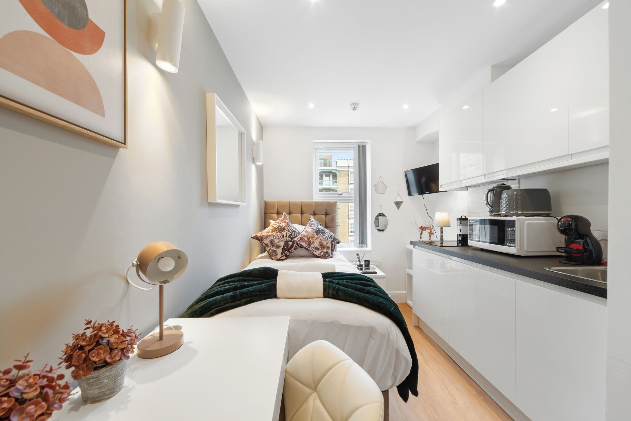 A modern bedroom with a bed, bedside table, lamp, and a view of the city.