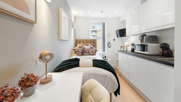 Et moderne soveværelse med seng, sengebord, lampe og udsigt over byen.