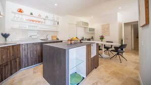 Een moderne keuken met een centraal eiland, inbouwplanken en een eethoek met stoelen.