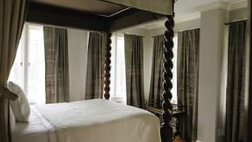A four-poster bed in a room with large windows and curtains.