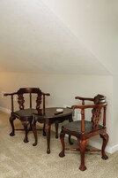 Un comedor con dos sillas de madera y una mesa, suelo alfombrado y pared blanca.