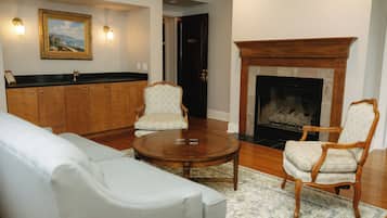 A living room with a fireplace, a sofa, two armchairs, a coffee table, and a painting on the wall.
