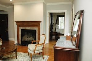 A room with a fireplace, a wooden chair, a table, and a mirror. - The Belvedere Estate (Saugatuck)