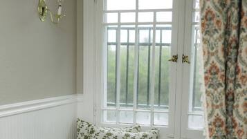 A room with a window seat, a white door, and a patterned curtain.