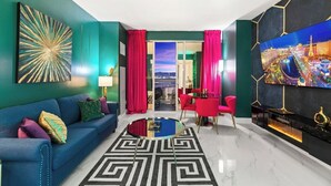 Een moderne woonkamer met een blauwe bank, een ronde salontafel en een televisie aan de muur.