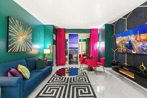 A modern living room with a blue sofa, a round coffee table, and a TV on the wall.
