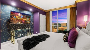Een hotelkamer met een groot bed, een aan de muur bevestigde televisie en uitzicht op de stad door het raam.
