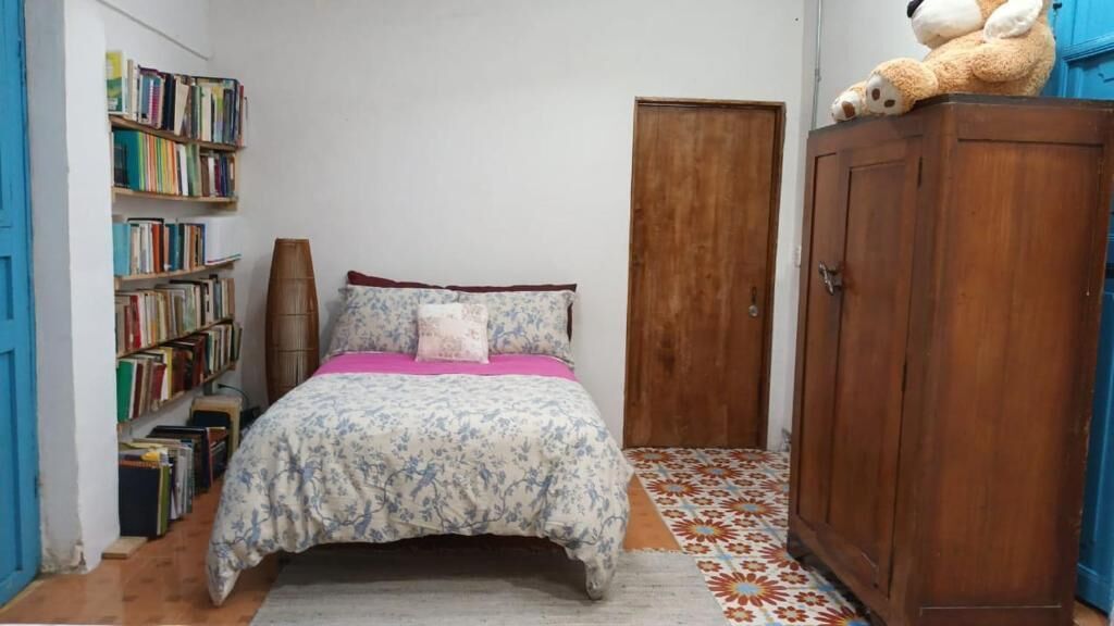 A bedroom with a bed, a bookshelf, a wardrobe, and a teddy bear.