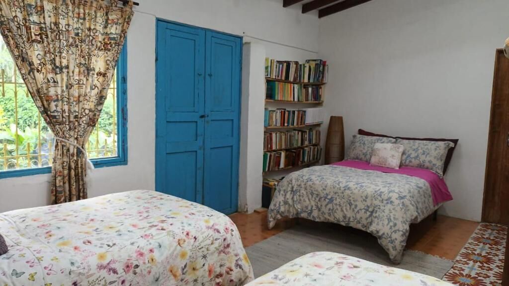 Un dormitorio con dos camas, una estantería y una puerta azul.