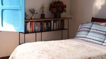 Een slaapkamer met een bed, een blauwe deur, een boekenkast en een kroonluchter.