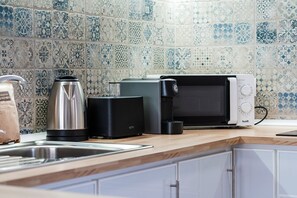 A kitchen with a coffee maker, toaster, and microwave on a wooden countertop. - GuestReady - Casa Avó Celeste (Faial)