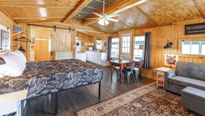 Um interior acolhedor de cabana com uma cama, área de refeições e sala de estar.