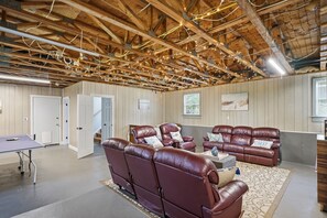 Ein geräumiges Zimmer mit hoher Decke, Holzbalken und einer Sitzecke mit Ledersofas.