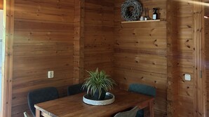 A wooden interior with a dining table, chairs, and a potted plant. - Scandinavian Bungalow with a Veranda on the Water! (Hulshorst)