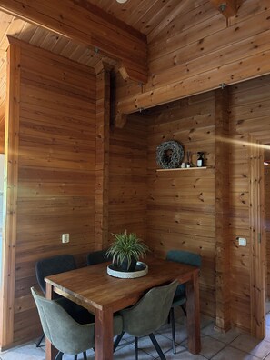 A wooden interior with a dining table, chairs, and a potted plant. - Scandinavian Bungalow with a Veranda on the Water! (Hulshorst)