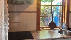 A kitchen with a window, a stove, and a sink. - Scandinavian Bungalow with a Veranda on the Water! (Hulshorst)
