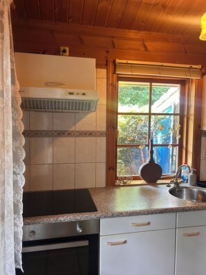 A kitchen with a window, a stove, and a sink. - Scandinavian Bungalow with a Veranda on the Water! (Hulshorst)