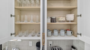 Eine Küche mit offenen Schränken, die Gläser, Tassen und eine Kaffeemaschine zeigen.