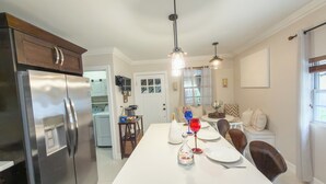 A modern kitchen with a central island, stainless steel appliances, pendant lighting, and a dining area with a white table and chairs. - Wynwood/Midtown Retreat–Walk to Miami Attractions! (Miami)