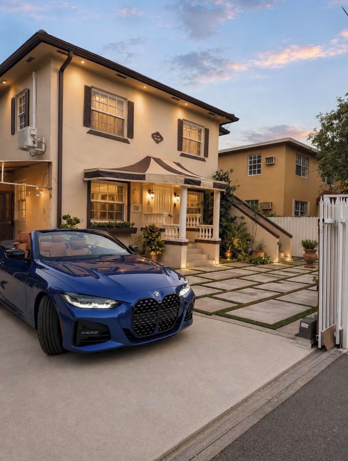 A two-story house with a covered porch and a blue car parked in front.