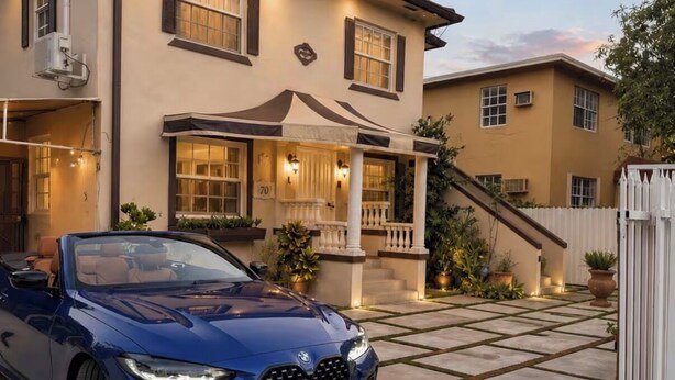 A two-story house with a covered porch and a blue car parked in front. - Wynwood/Midtown Retreat–Walk to Miami Attractions! (Miami)