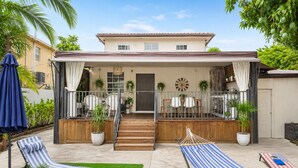 A two-story house with a covered patio, outdoor seating, and a hammock. - Wynwood/Midtown Retreat–Walk to Miami Attractions! (Miami)