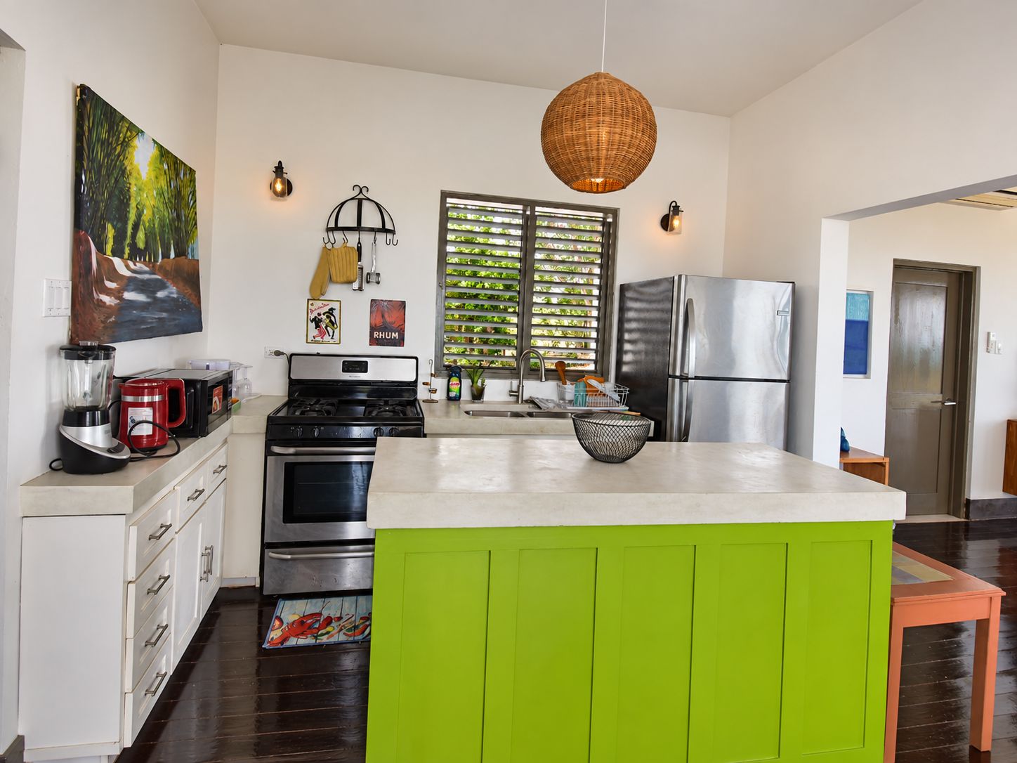 A modern kitchen with a central island, stainless steel appliances, and a view of greenery outside.