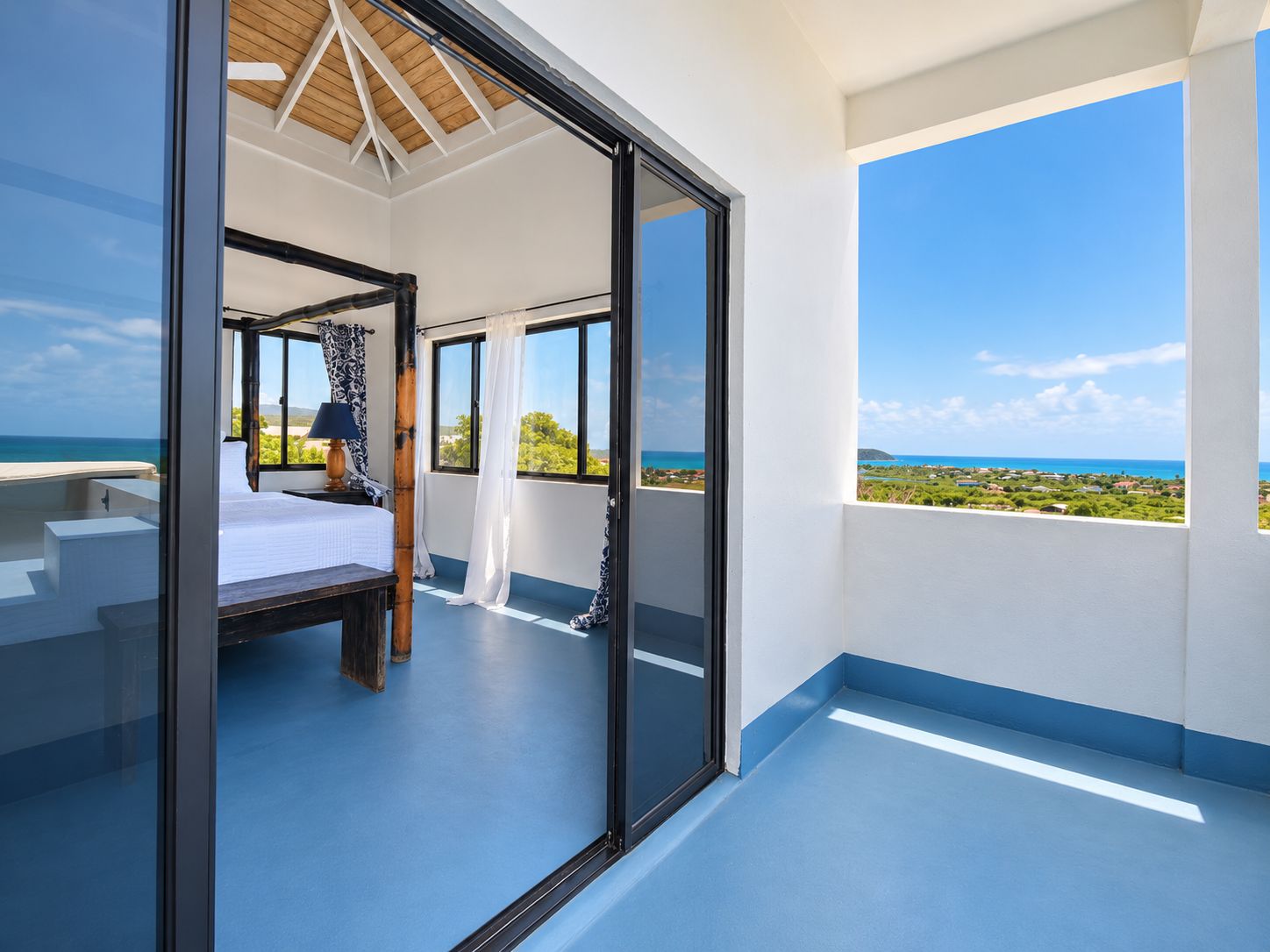 A bedroom with a bed, a nightstand, and a window with a view of the ocean.