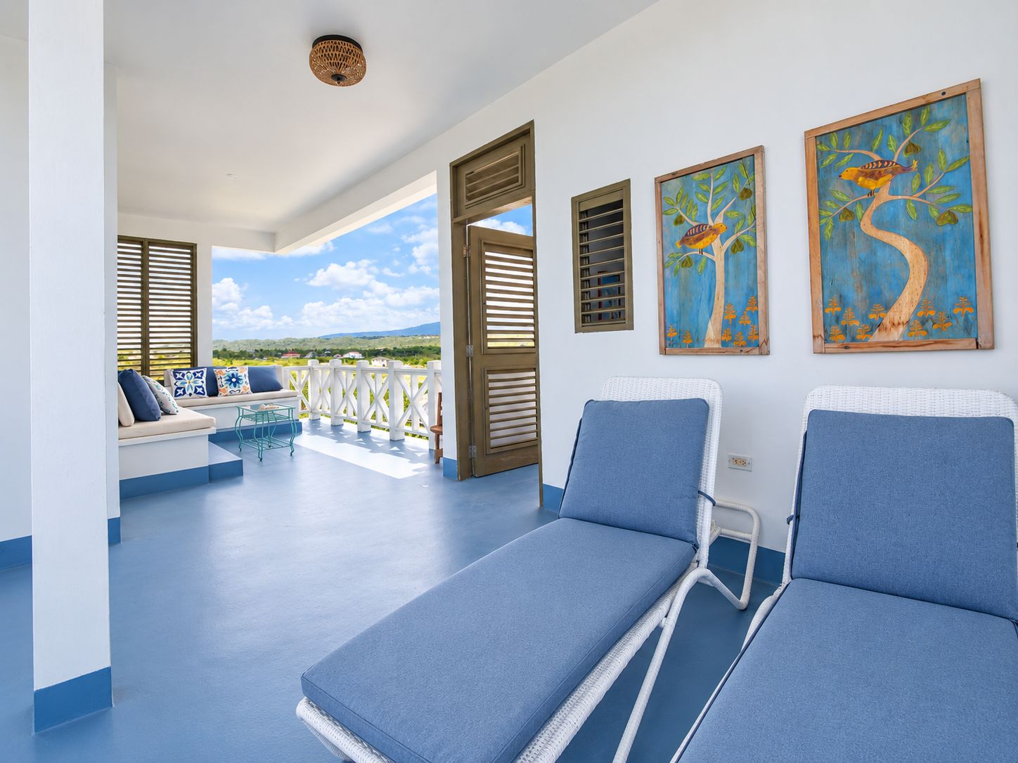 Un balcón con vistas al paisaje, un espacio de descanso con cojines y dos sillones de relax.