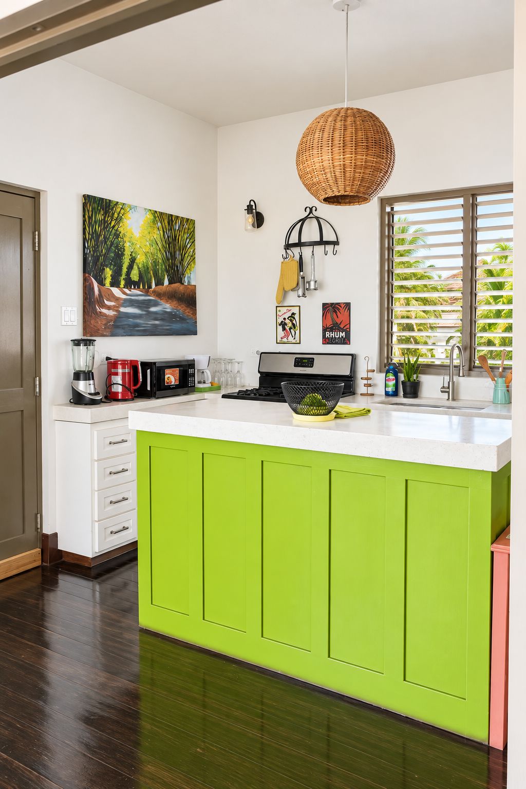A kitchen with a white countertop, green cabinets, a hanging basket light, a painting, and a window with blinds.