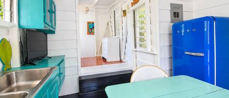 A kitchen with teal cabinets, a blue refrigerator, and a dining area with a teal table.