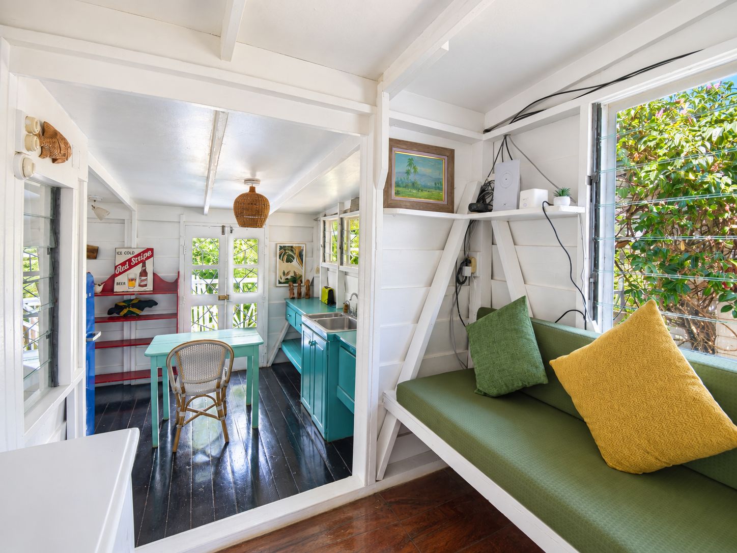 A compact living space with a kitchenette, a dining area, and a seating area with a view of greenery.