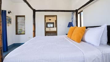 Une chambre à coucher avec un grand lit, une table de chevet, un miroir et une fenêtre avec des stores.